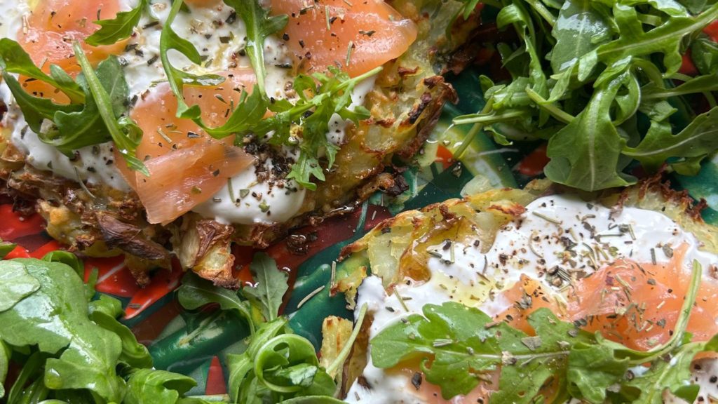 Tarte de pommes de terre écrasées garnie de saumon fumé, fromage frais et roquette